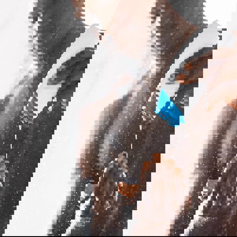 Person in shower squeezing product out of a bottle