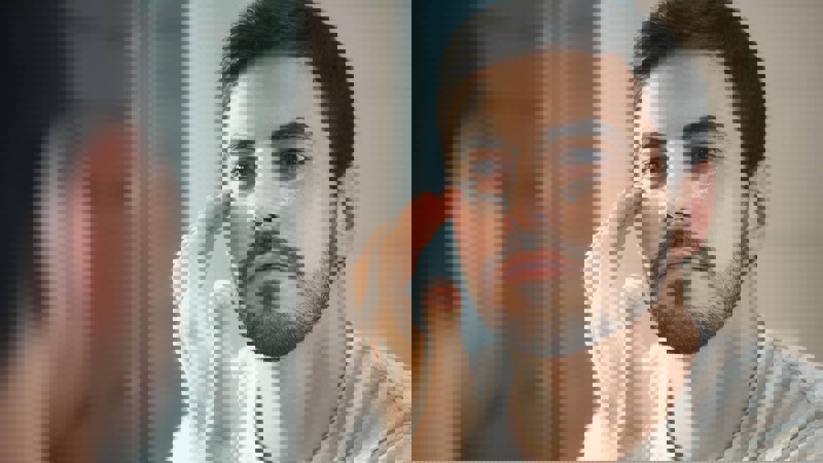 Person applying eye cream in the mirror